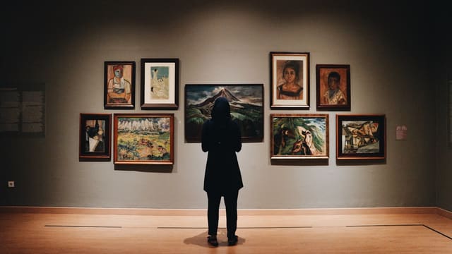 woman in black coat standing in front of paintings