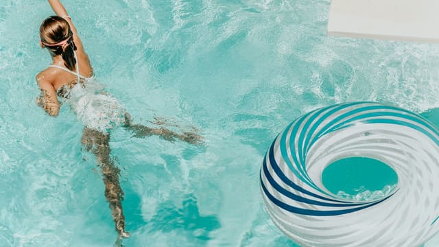 girl wearing swimsuit and swims in swimming pool