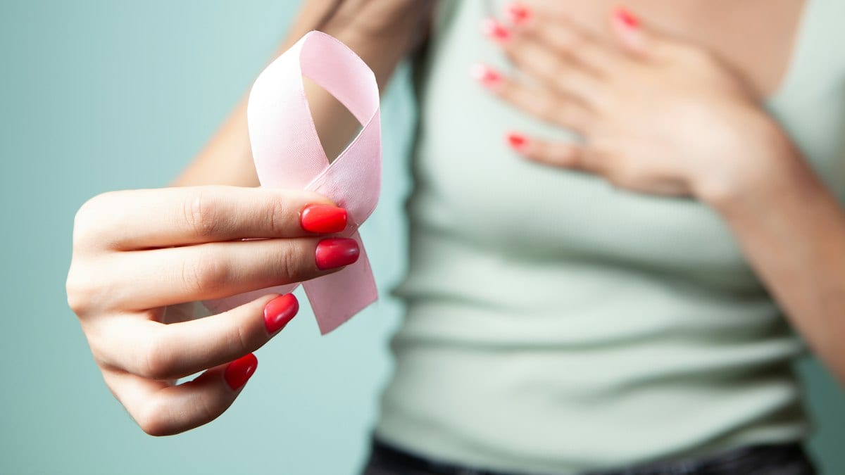 Woman holds pink ribbon for breast cancer awareness