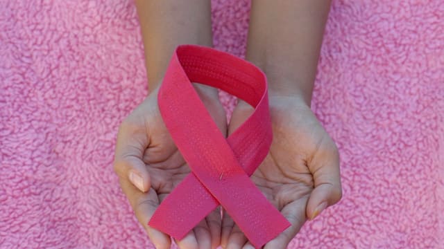 Personne portant un ruban rose à la main gauche
