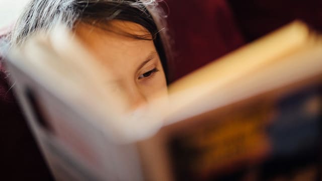 Enfant lisant un livre dans une bibliothèque, ateliers lecture jeunesse.