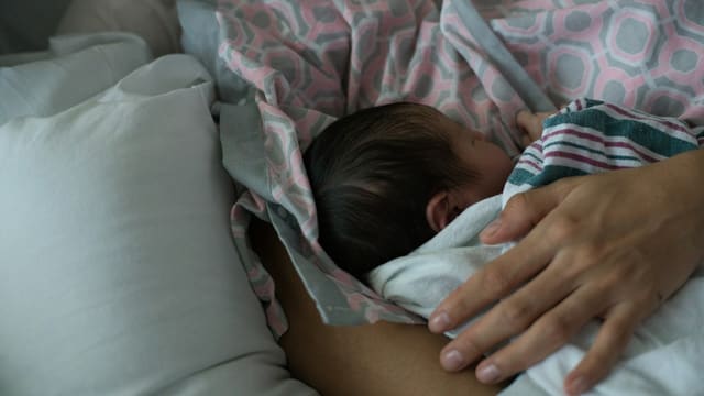 Mother holding a newborn baby while breastfeeding.