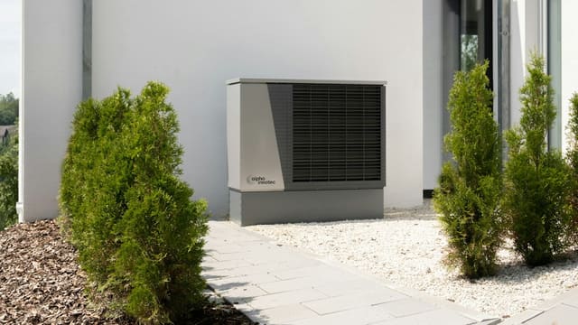 Unité extérieure d'une pompe à chaleur air/eau installée contre la façade d'une maison individuelle.