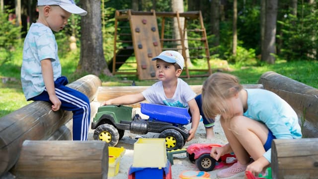 2 boys sitting on red and black ride on toy car