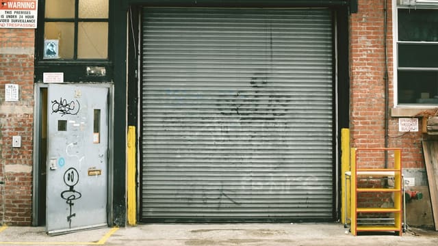 Rideau métallique baissé devant une façade de brique, type d'équipement que l'aide régionale permet de financer à moitié