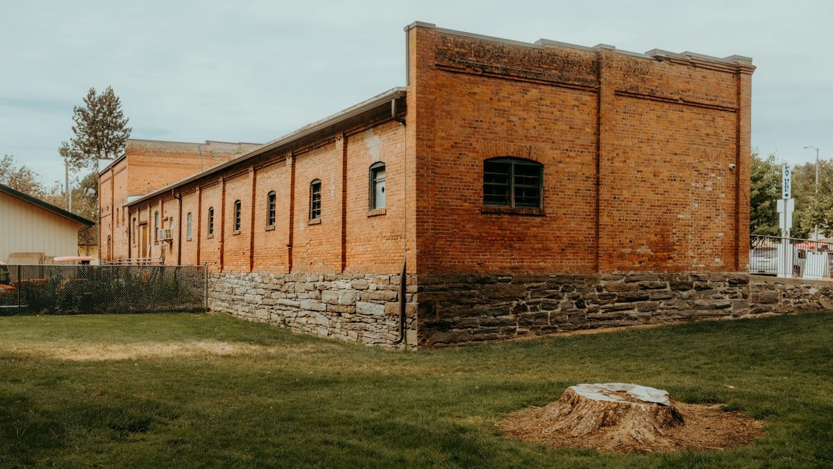 Ancien bâtiment en brique avec fondations en pierre et cour herbeuse