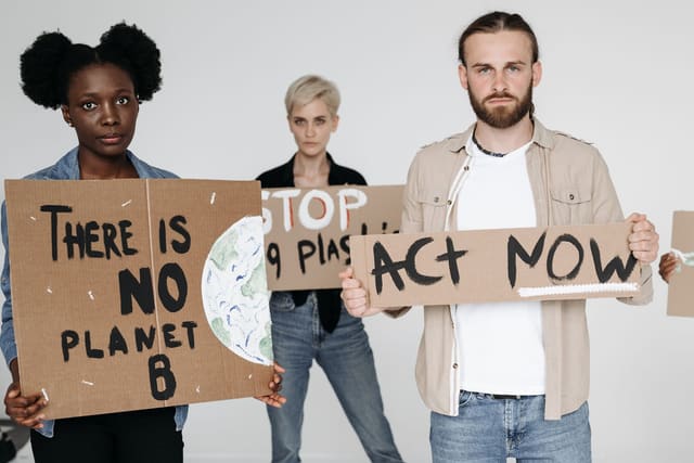 Activists hold cardboard signs advocating for environmental protection and climate action.