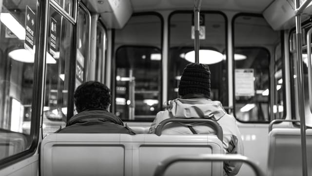 man in black knit cap sitting on bus seat