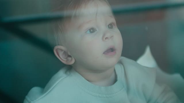 Gros plan sur le visage d'un jeune enfant, les yeux levés et la bouche entrouverte, comme happé par un écran.