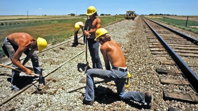 a group of men standing on top of a train track