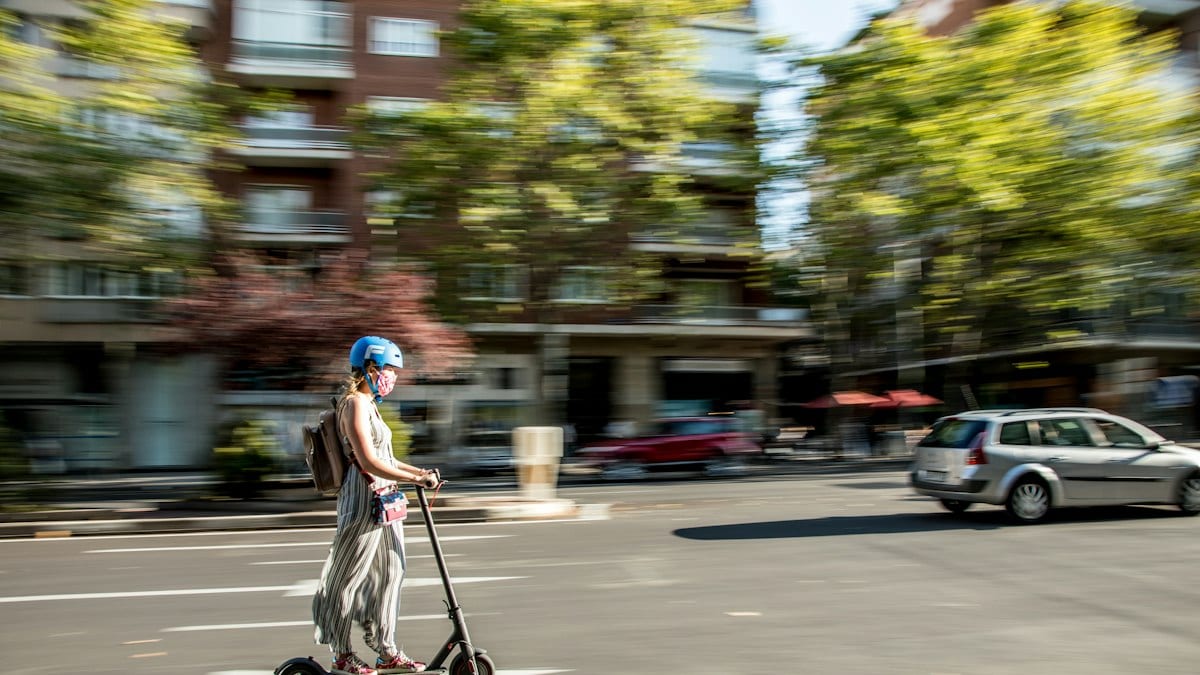 Enfant en robe rose chevauchant une trottinette sur la route