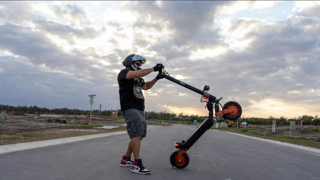 Man in helmet holding electric scooter outdoors