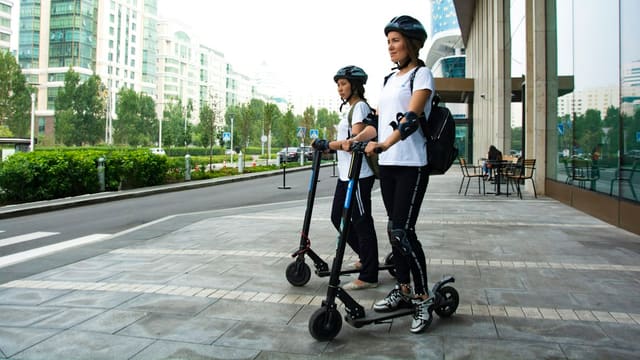 Deux femmes chevauchant des trottinettes