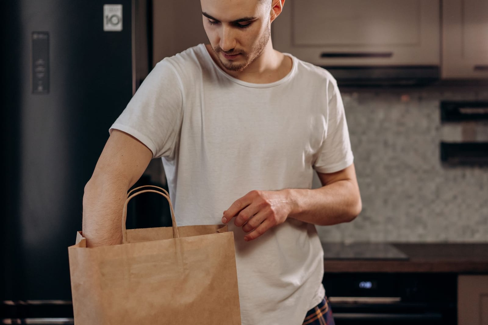 Homme en chemise blanche déballant des courses d'un sac en papier