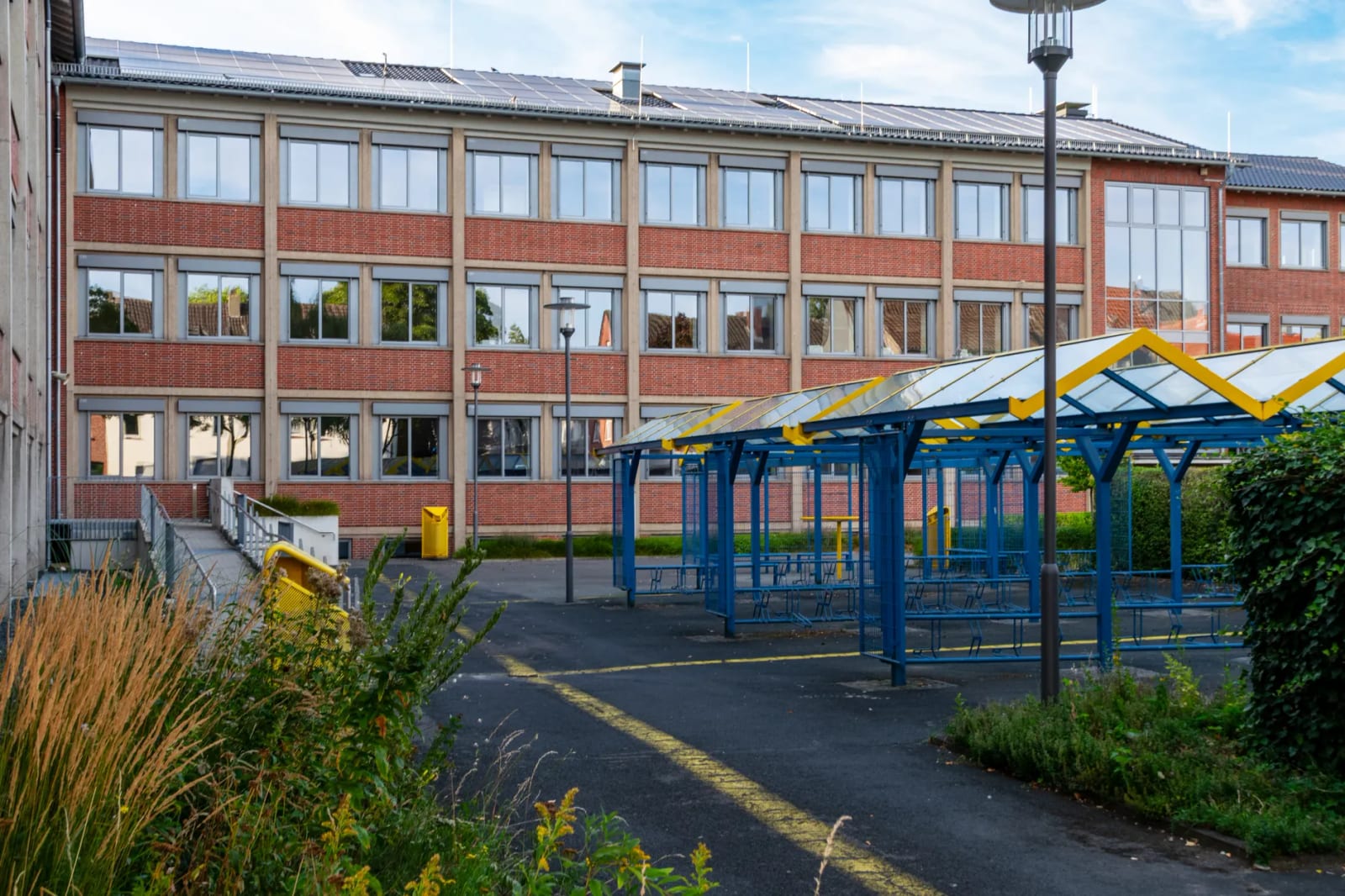 Façade d'un collège contemporain à l'architecture durable, avec panneaux solaires et abris à vélos