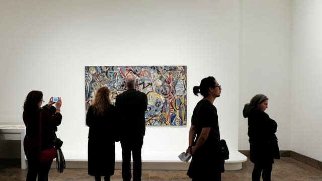 Groupe de personnes debout devant un tableau