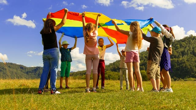 Enfants jouant avec un parachute coloré sur l'herbe