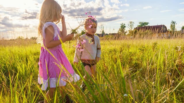 girl in pink and white dress standing on green grass field during daytime