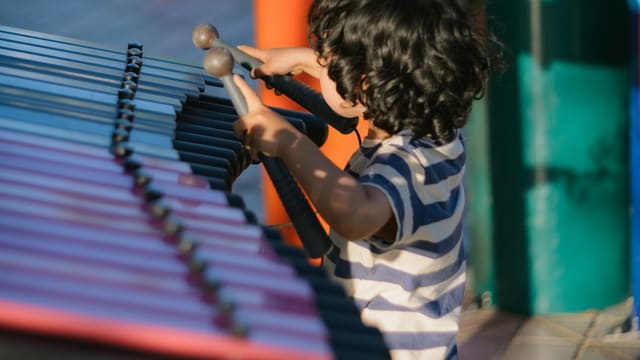 Un enfant joue d'un instrument de musique devant des percussions colorées
