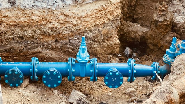 a blue pipe laying on top of a pile of dirt