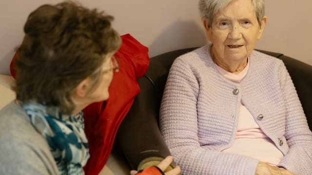 Two elderly women sitting and talking
