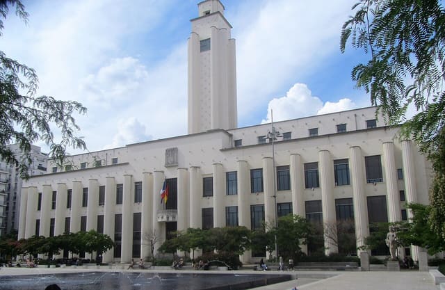 La façade de l'hôtel de ville de Villeurbanne et sa tour, vues depuis la place, avec le bassin au premier plan.