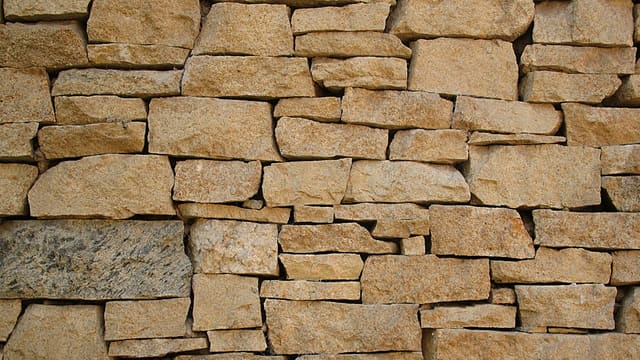 Mur en pierres massives empilées, illustrant le matériau brut utilisé pour la résidence Albamiel