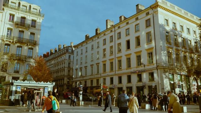 Vibrant city life on a sunny day in Lyon, France, capturing pedestrians and historic architecture.